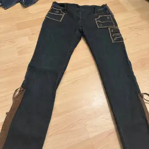 Vintage Lågmidjade Jeans som öppnas från sidan. Design ifrån Alessandro De Benedetti ”dolls” Midjemått: 76cm.  Innerbenslängd:83cm VIKTIG INFO: dom är inte så stretchiga, SMALL IN SIZE 