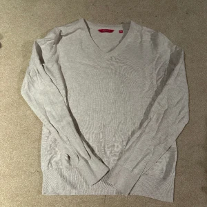 Stickad V-ringad tröja - En långärmad beige stickad tröja med V-ringning