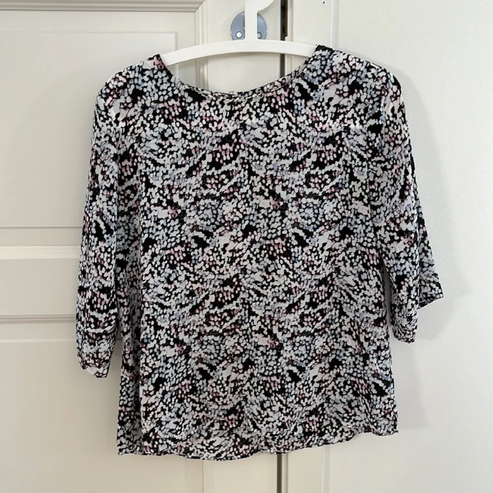 Fin topp i flera färger (vitt, svart, rosa och ljusblå) med halvlång ärm i polyester. Stl 36. Puserot.