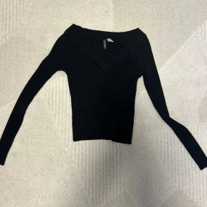 Ribbad tröja  - Svart ribbad tröja med en V ringning. Kortare i modell. Storlek S