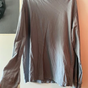 Grå långärmad tröja  - Grå långärmad tröja köpt på H&M, använd ett fåtal gånger sen den köptes. Har inga tecken på användning. Köptes från herravdelningen och är en medium. Ser hur den sitter på bild 2, är både lång i armen samt går lång ner över överkroppen. Finns på fler