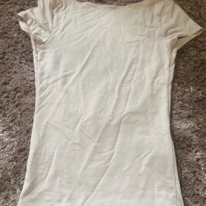 Öppen rygg t-shirt  -  Beige t-shirt som har öppen rygg. Säljer då den aldrig har kommit till användning. Det är lite söndrig vid armhålan vilket vissas på sista bilden. Annars är den jätte bra i skicket. Den är normal i sin storlek.