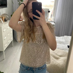 Blus - Glitter blus köpt från Lindex barn avdelning i storlek 170 men passar en XS/S. Köpte i vintras så säljs ej längre om jag inte mina fel köpte jag den för 250kr. Färgen är typ beige/guld, nästan champagne färgad. Endast använd 1 gång.