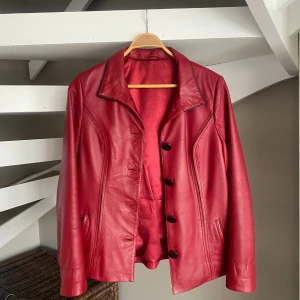 Röd skinnjacka i äkta läder - Röd skinnjacka i vintagemodell i äkta läder. Tillhörde min mormor och köptes in sommaren innan hon gick bort, därmed sparsamt använd. Skräddarsydd efter henne men passar S-M.  Nypriset var 4500kr, säljes endast då den är för liten för mig. 