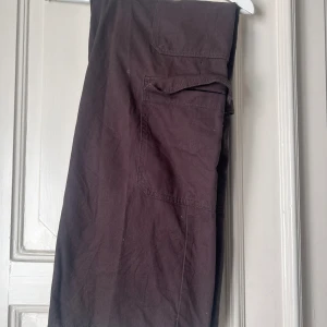 Cargobyxor - Bruna cargobyxor med fickor och knapp framtill. 