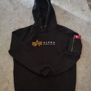 Svart Alpha hoodie som inte används. Fint skick då den bara är använd fårtal gånger. Storlek L men passar M, nypris 1000 kr.