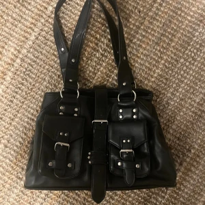 Y2k väska  - Fin svart väska som jag tyvärr inte längre använder. Väldigt praktisk med många fack. Spännet i mitten har en magnet så den är lätt att öppna o stänga 🌟