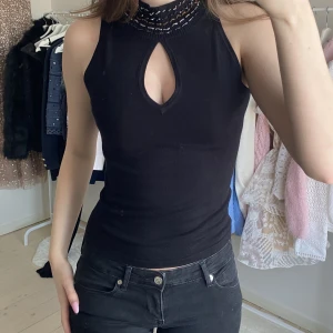 Svart polo med pärlor - Snygg polo tröja med utskärning vid brösten och pärlor uppe på kragen. Perfekt till vardags och till fest❤️