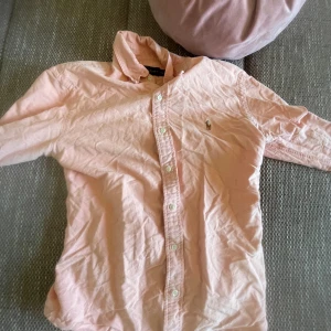 Ralph Lauren Pikétröja/skorta - Hej, säljer denna dina ljusrosa som passar perfekt med vita/beige som byxor/shorts! Säljer pga den har blivit för liten för mig🥲