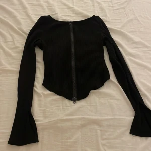 Svart topp - En långärmad tröja med dragkedja, du kan bestämma om du vill ha den öppen helt eller stängd. Öppen nere eller uppe. Använd en gång.