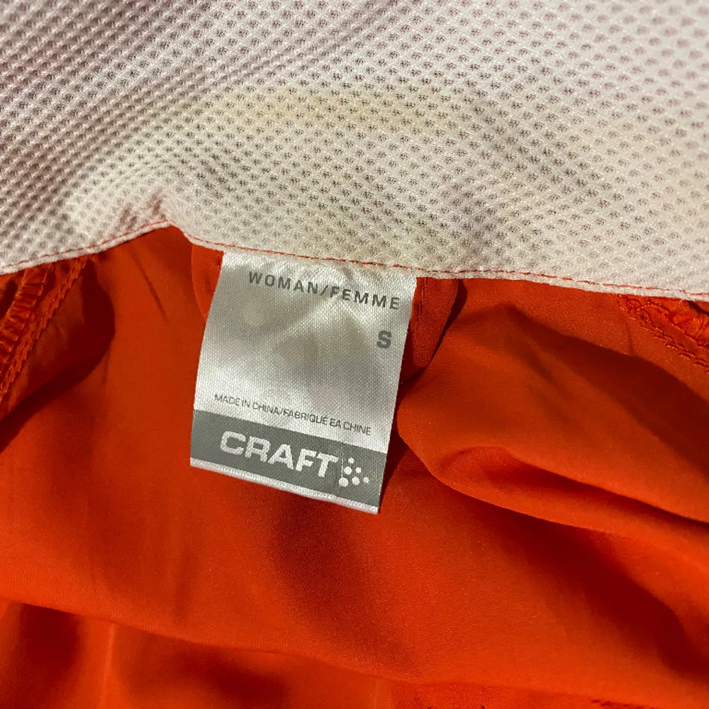 Träningsjacka från Craft, orange/grå. Liten fläck vid nacken, men går säkert bort i tvätten. Dragsko så du kan välja om du vill ha den kortare.. Hupparit & Collegepaidat.