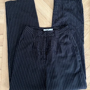 NA-KD Ksotymbyxor - Jättefina och uppklädda svarta raka kostymbyxor med vita ränder ifrån NA-KD💕 Sitter superfint på kroppen och är i storlek 34💕 Jag är 173cm och de sitter perfekt i längden på mig💕