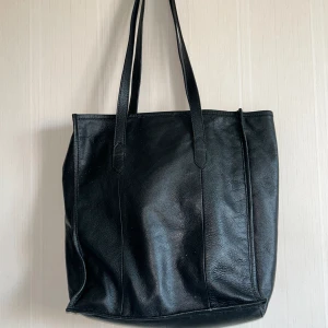 Svart läderväska  - Höjd 37cm Längd 34cm Vidd 12cm Handtag 28cm Bomullstyg inuti 