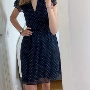 En mörkblå klänning med vita ”prickar” på. Från H&M, i fint skick