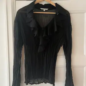 En topp/skjorta/blus, svart genomskinlig med volang och silverdwtaljer. Väldigt fin! Passar S-L beroende på hur man vill att den ska sitta. Lite oversized fit