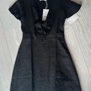 Klänning - En superfin svart klänning i linne. Denna klänning har jättefin snörning framtill och är i storlek 36. Helt oanvänd. 