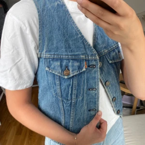 Jeansväst från Levis  - En jeansväst från Levis i fint skick! Köpt på en bloppis men verkar knappt vara använd. Står att det är storlek M men skulle säga att den passar S bättre