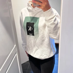 Calvin Klein hoodie  - Vit hoodie från Calvin Klein med tryck på. Passar super bra till en fin sommarkväll! Storlek 14år. Jag har storlek 158 i vanliga fall och passar mig bra. Hoodien är knappt använd utan bara legat i en låda. Nypris 899kr