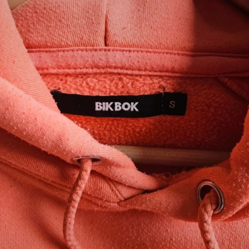 En jättefin korallfärgad hoodie från Bikbok i storlek S Använd några gånger men fortfarande i bra skick dock lite små noppror men inget man tänker särskilt mycket på Skriv om ni har frågor, vill ha fler bilder eller har prisförslag🧡. Hoodies.