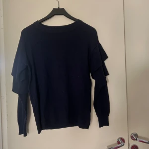 Stickad tröja - Stickad tröja med volang detaljer på ärmarna.