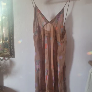 Vintage klänning i transparent material  - Egen klänning med väldigt bussäte 80tals typ av mönster på. Silhuett lite 20tal. Broderade pärlor. I ett använt skick.