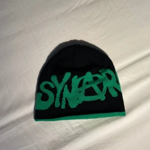 Syna world mössa synarchy  - Den är 10/10 skick aldrig andvänd kan göras till grön och svart 100 % äkta 