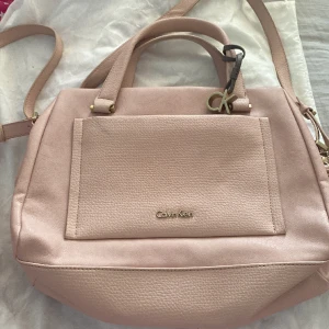 Calvin klein väska - Fint skick, har en liten fläck på framsidan (se sista bilden) och en liten fläck på rämmen (se mitten bilden) annars så jätte fint skick och as snygg väska!