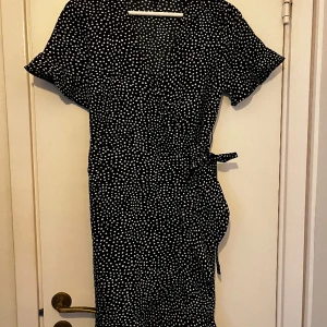 Prickig sommarklänning - En prickig omlottklänning från Vero Moda. Den är omlott som man knyter i midjan så det går att ha den tajt eller löst om man hellre vill det. Säljs pga att jag sällan använder den. Storlek S. Tveka inte att höra av dig om du har frågor