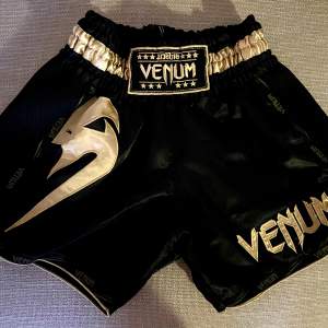 För olika typer av kampsport, boxning, muay thai, kickboxning. Shorts från Venom. Svart och guld. 
