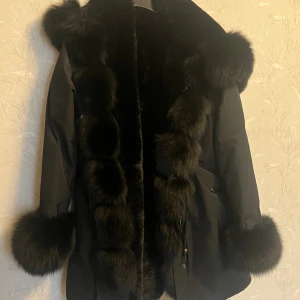 Dolly Park Jacka - Dolly  Parka har ett  tjockt varm foder inuti som värmer bra på   vintern. Alla  pälsdetaljer är avtagbara. Det vattentäta skalet är   perfekt att använda  som vår- eller tidig höstjacka. Fickor finns på   sidan och snöre för att dra åt midjan . 