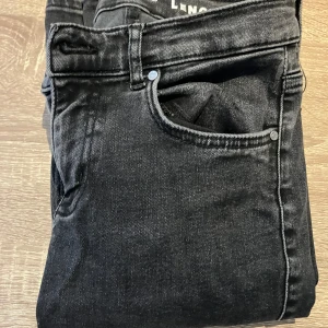 Svarta jeans med låg midja och flare - Ett par svarta jeans med låg midja och flare. Jeansen har en dragkedja och knappar framtill samt fickor både fram och bak.