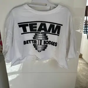 En vit croppad t-shirt från Better Bodies med svart text på framsidan och baksidan. T-shirten har korta ärmar och en lösare passform.