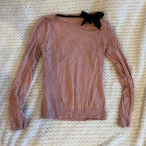 Rosa tröja med rosett - Gammalrosa tröja med supergullig rosett-detalj. Köpt secondhand och använt själv 2-3 ggr. Köpte utan lappar så osäker på märke och strl men passar mig med XS-S!