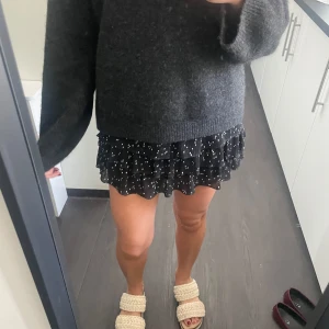 Svart kortkjol med vita prickar - En svart kortkjol med vita prickar och volangdetaljer. 