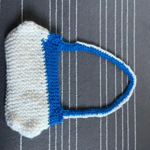 Handgjord stickad väska i blått och vitt - En handgjord virkad väska i blått och vitt. Väskan har en enkel design med ett handtag och är rymlig nog för att bära personliga tillhörigheter. Perfekt för vardagsbruk. 