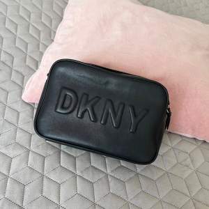 En svart axelremsväska från DKNY i bra skick med guld detaljer. 