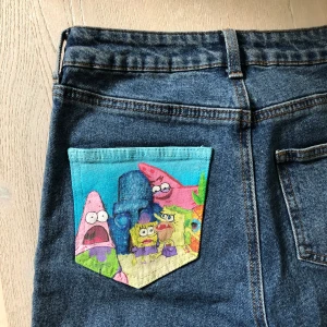 Jeans med Simpsons & Spongebob motiv - Motiven är målade med tygfärg men om man ska tvätta dem, använd gärna strykjärn (med bakplåtspapper emellan) för att minska att det förstörs i tvätten.