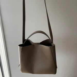 Väska från gina - Säljer min väska 22x25 cm. Sömmen har gått upp lite i ena kanten (syns på bild 1) och därav priset. Jättefin annars🌸 Skickar gärna fler bilder på defekten/väskan privat