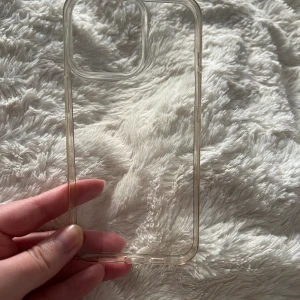 iPhone 13 pro skal - Skal till iPhone 13 pro, genomskinligt med en beige nyans. Från QX. Använt i ok skick. Få små repor men syns inte så tydligt, gick ej att ta bild på dessa. 