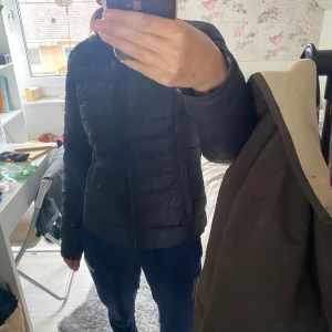 Svart pufferjacka - Säljer en svart pufferjacka som är perfekt för kalla dagar. Jackan är quiltad och har en dragkedja framtill. Den är långärmad och har en normal passform. Insidan är fodrad med grått material för extra värme. Perfekt för höst och tidig vinter!🥰