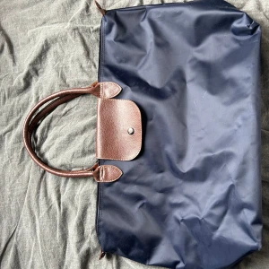 Stor Longchamp väska  - Säljer min stora Longchamp väska. Den säljes billigt pga att dragkedjan tyvärr saknas. Annars är den i superfint skick