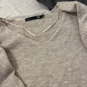 Beige stickad tröja från 15th - Säljer en supermysig beige stickad tröja från Lager 157. Den är i storlek M och har en v-ringad hals. Tröjan har långa ärmar och ribbstickade muddar vid ärmslut och nederkant. Perfekt för höst och vinter! 🧡 Har aldrig haft på mig den!