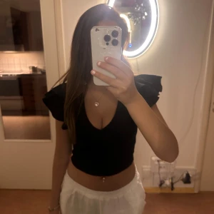 Svart kortärmad topp - En svart  topp med volangdetaljer på ärmarna och en djup v-ringning. Toppen är tight och väldigt söt💓💓