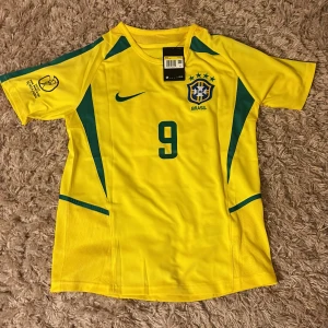 Gul Brasilien fotbollströja med nummer 9 - En sprillans ny Brasiliens nazario ronaldo (R9) retro fotbolls tröja från VM 2002 Japan/korea. Prislappen sitter fortfarande kvar och tröjan är helt oanvänd, vid fler frågor är det bara att skriva