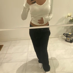 Vit ribbad långärmad tröja - En vit ribbad långärmad tröja med en v-ringad hals. Tröjan är tight passform och är tillverkad i ett stretchigt material.