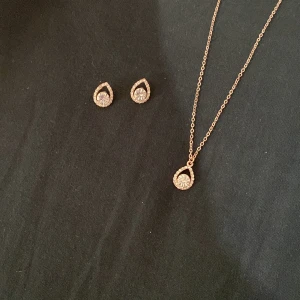 Elegant set med halsband och örhängen i roséguld - Säljer ett superfint set med halsband och matchande örhängen i roséguld. Både halsbandet och örhängena har en droppformad design med glittriga detaljer. Perfekt för fest eller en speciell kväll! ✨priset går att diskutera!