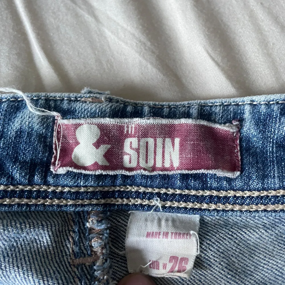 Säljer ett par snygga blå jeans från & Soin i storlek 26. De är i bra skick och har en klassisk femficksdesign med dragkedja och knapp framtill. Perfekta för vardagsbruk och kan matchas med nästan vad som helst!. Jeans & Byxor.