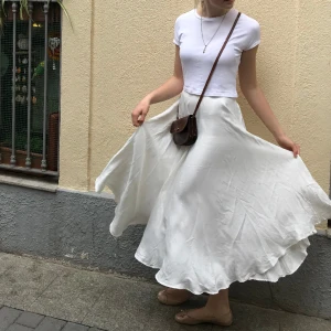 Vit kjol - Luftig, vit lång kjol från H&M. Storlek 36. Använd några gånger. Medelhög midja, materialet har en lätt lyster, lite pärlemorskimrande.