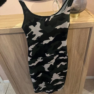 Militär klänning  - Figursydd klänning i militär mönster, har en slits bak 