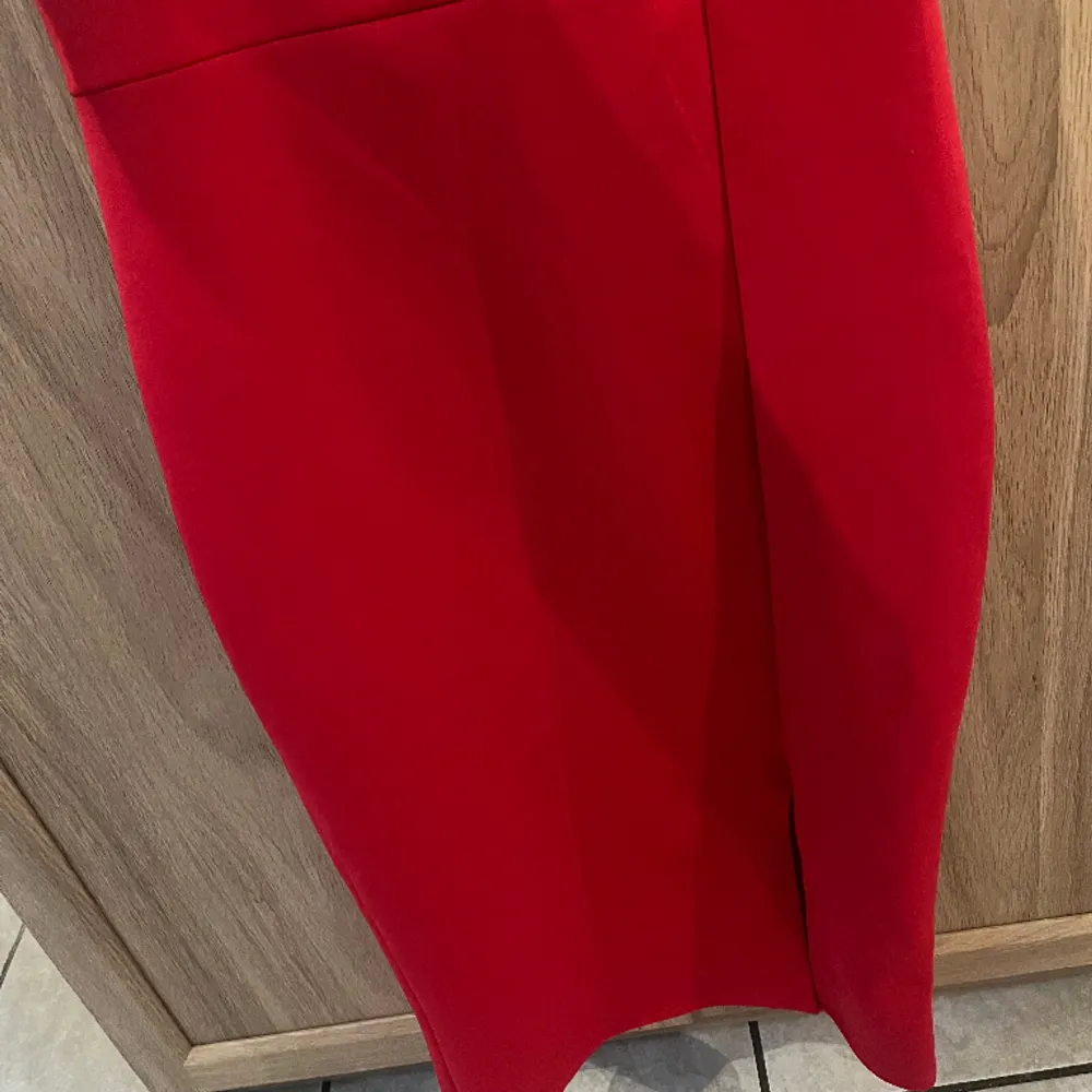 Figursydd röd klänning ifrån Nelly  Längden är ungefär till knäna och har en slits vid vänster sida av benet. Klänningar.